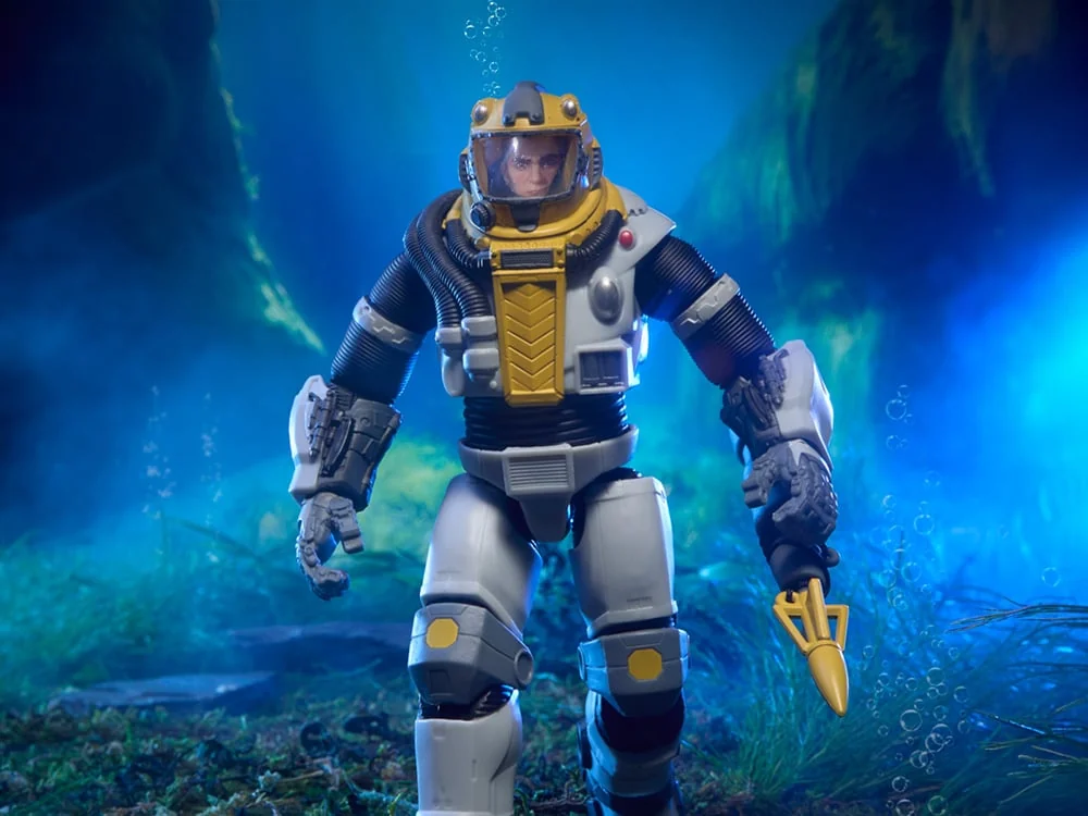 Classified Series Deep Six in a sealed deep-sea diving suit with a yellow helmet and clear dome, walking an underwater sea floor with a gold trident in one hand
