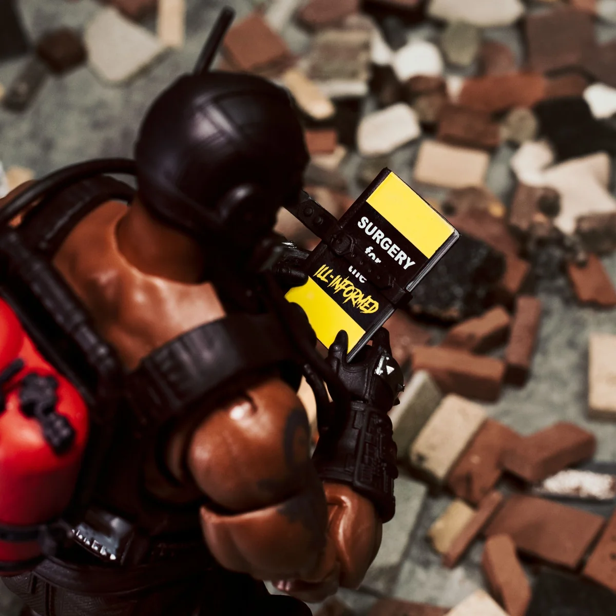 Flatline seen from above, reading a yellow and black book titled Surgery for the Ill-Informed