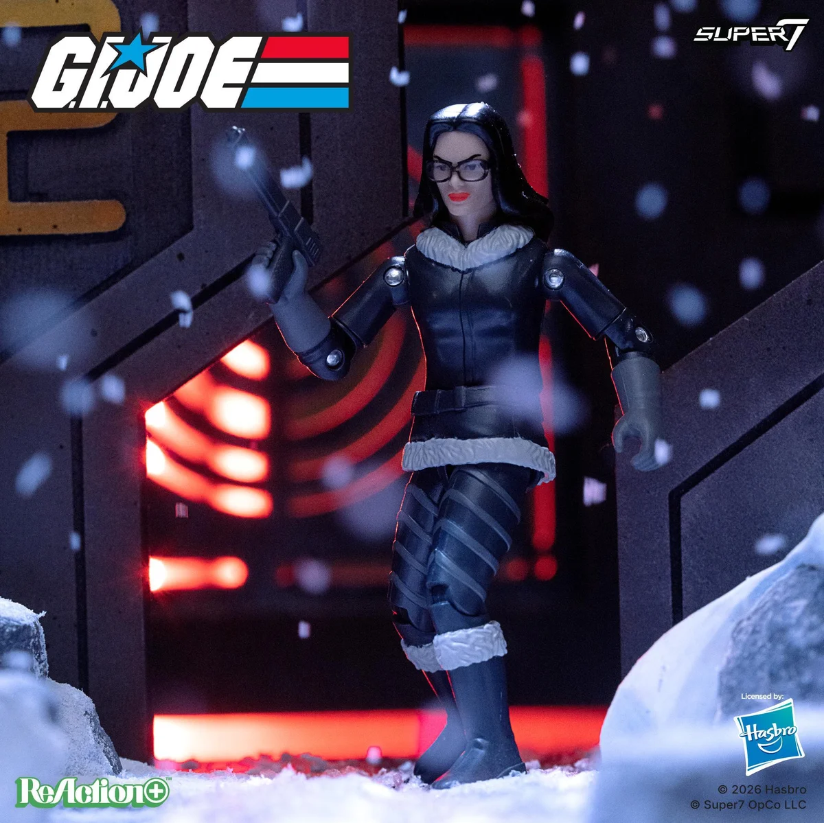 The G.I. Joe ReAction+ Baroness (Arctic) figure in a snowbound Cobra installation doorway, wearing a black coat with white fur trim at the collar, waist and boots, holding a pistol, with red interior lighting behind her