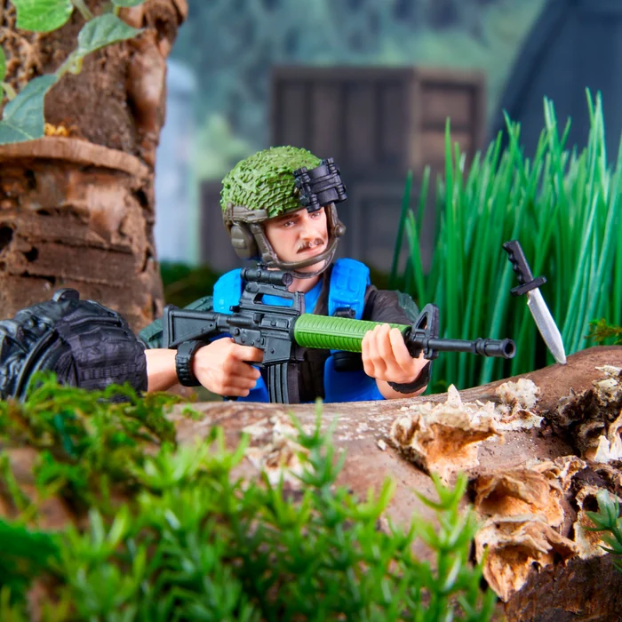 Footloose in his foliage-band helmet taking aim with the green-stocked assault rifle from behind a log
