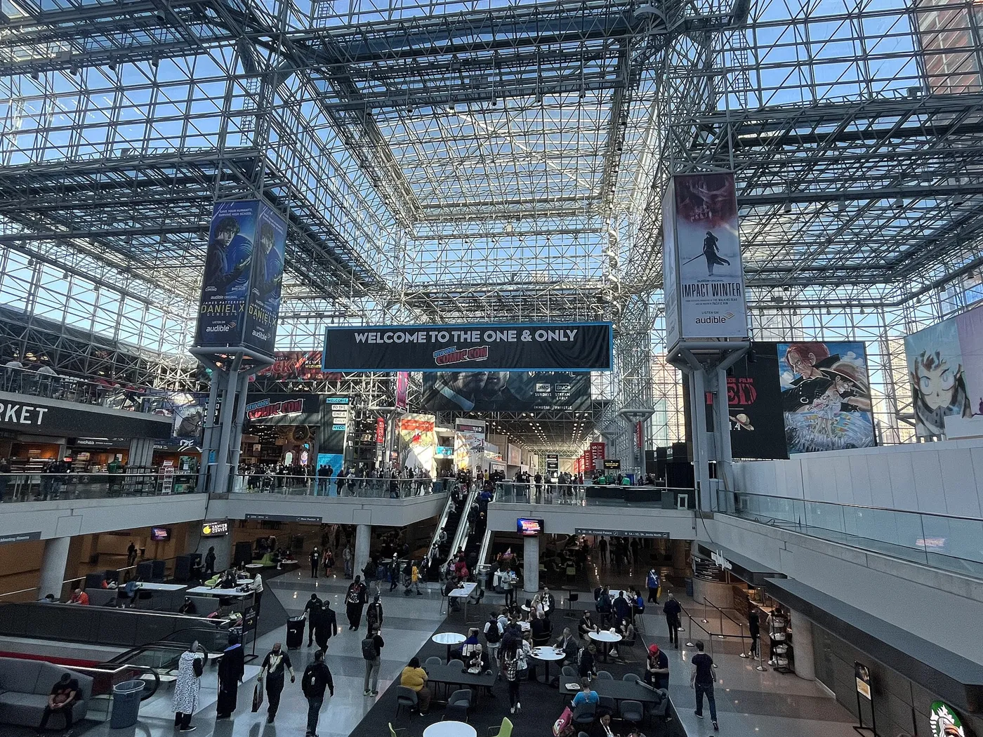 The glass-roofed atrium inside the Javits Center during New York Comic Con 2022, with show banners overhead